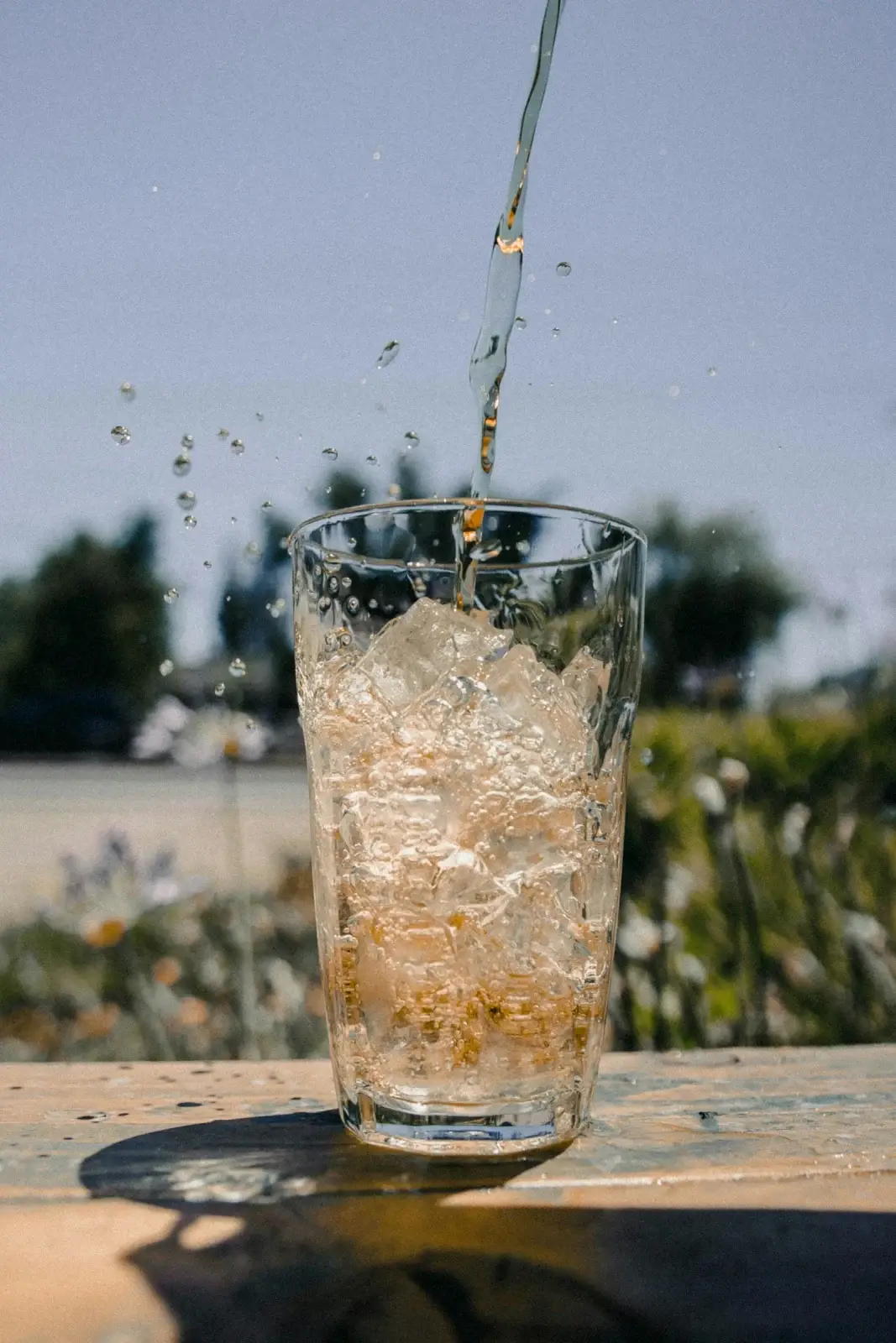 Liquid pouring into a glass full of ice outdoors